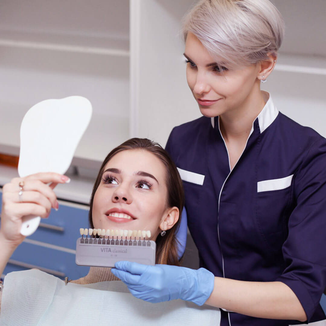 Врач-стоматолог демонстрирует результат отбеливания стоматолог показывает результат отбеливания